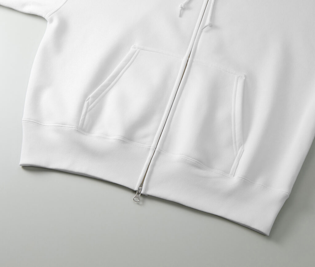 岸和田のカジュアルプリント(カジプリ)がオススメするユナイテッドアスレ社のパーカー(品番562101)の裾部分の拡大写真
ボディカラーはホワイト
着脱が簡単なジップタイプのパーカー
今流行りのボックスシルエット型
カジプリはオリジナルグッズ作成が得意です!